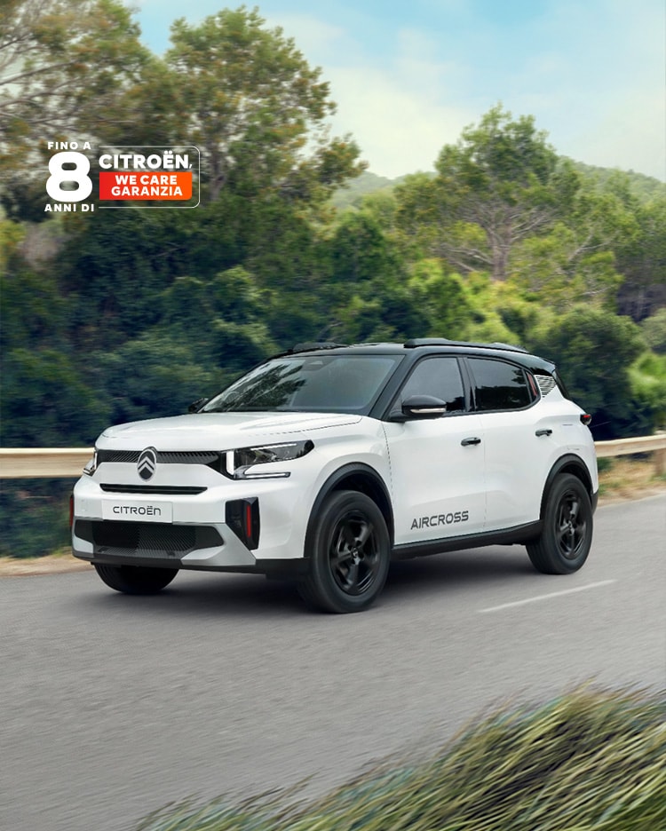 Vista posteriore a tre quarti sul mare e in guida su una strada forestale della Citroën ë-C3 Aircross SUV elettrica che mette in evidenza il design premiato e la copertura di 8 anni per una mobilità conveniente.