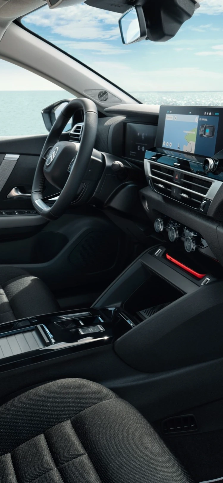 Abitacolo anteriore della Citroën ë-C4 X che mostra i sedili, la plancia e il panorama sul mare attraverso i finestrini